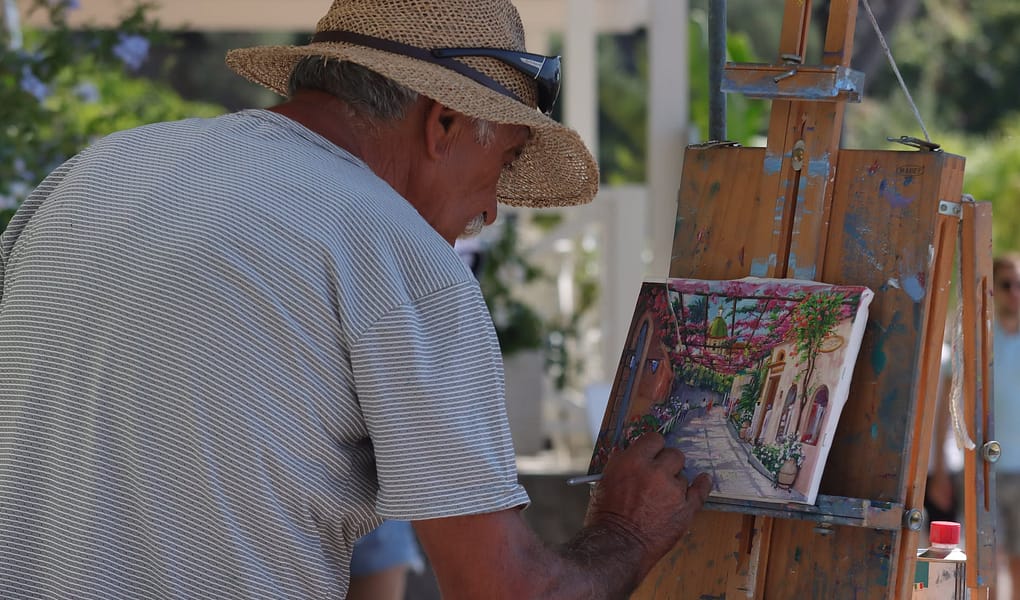 man in brown hat doing a painting