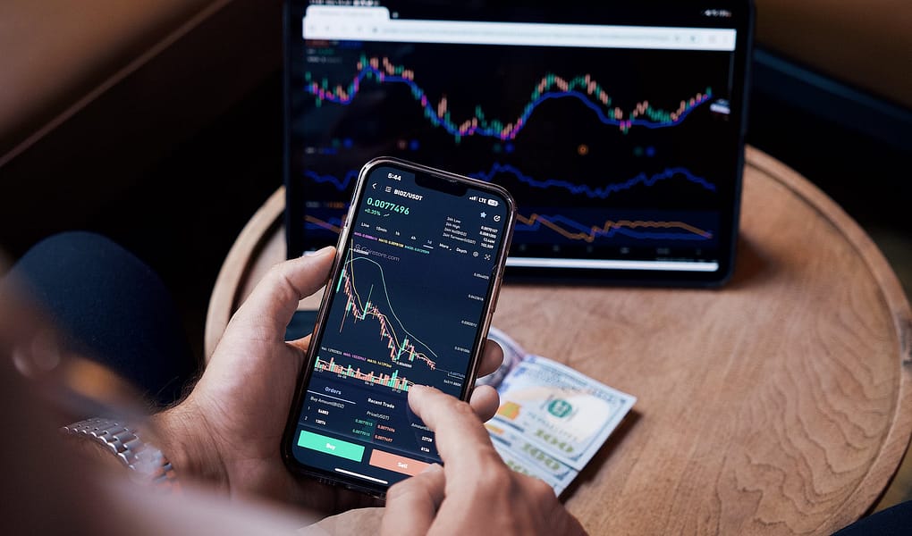 man looking at the stock charts on the phone and tablet