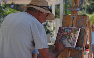 man in brown hat doing a painting