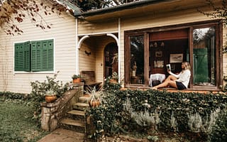 photo of woman sitting on window holding book