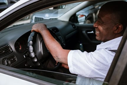 man in white dress shirt driving car