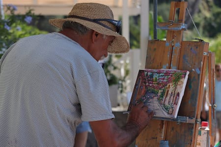man in brown hat doing a painting