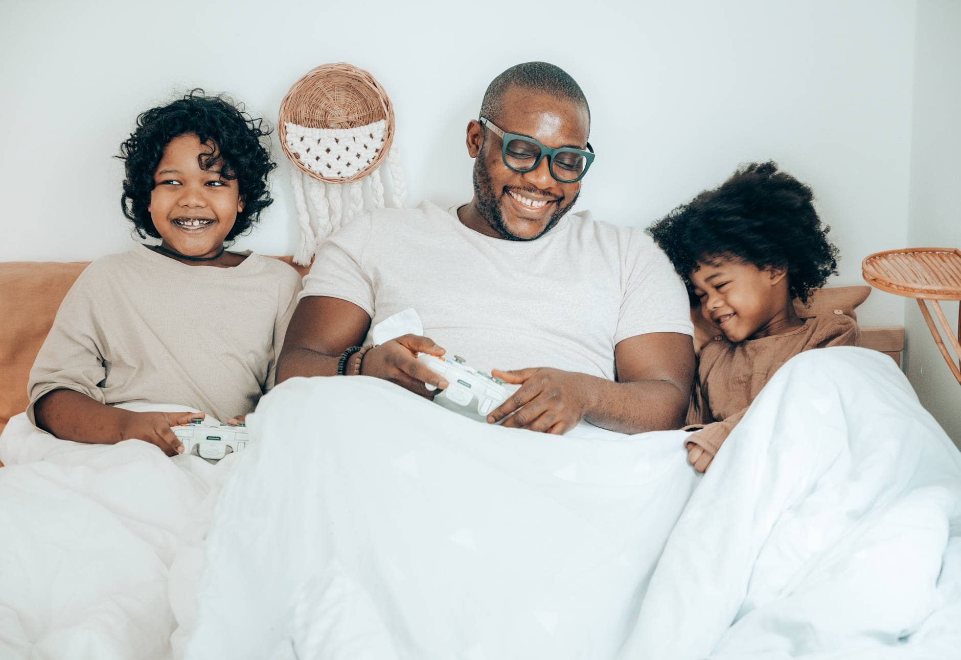 happy black father with kids resting in bed together