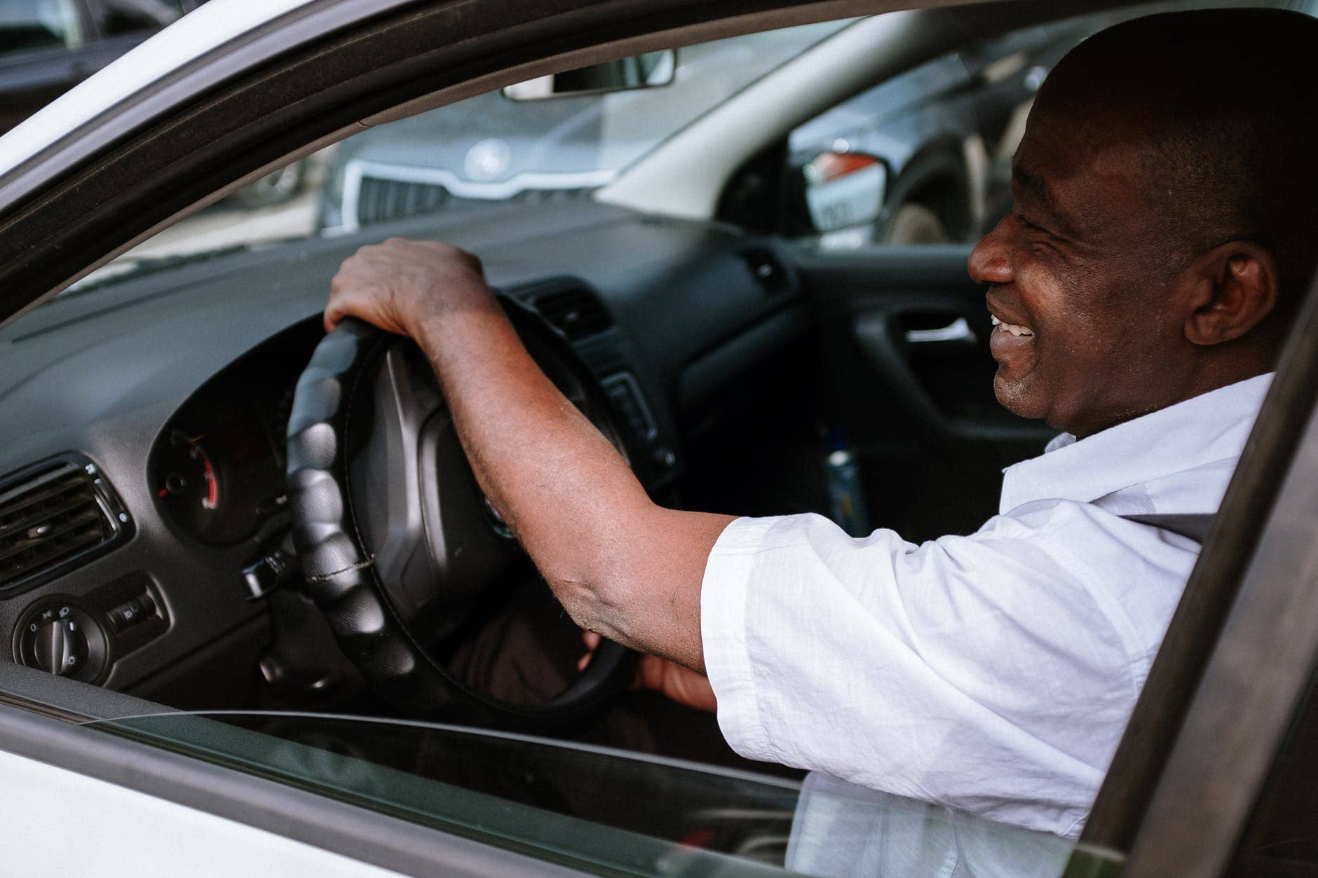 man in white dress shirt driving car