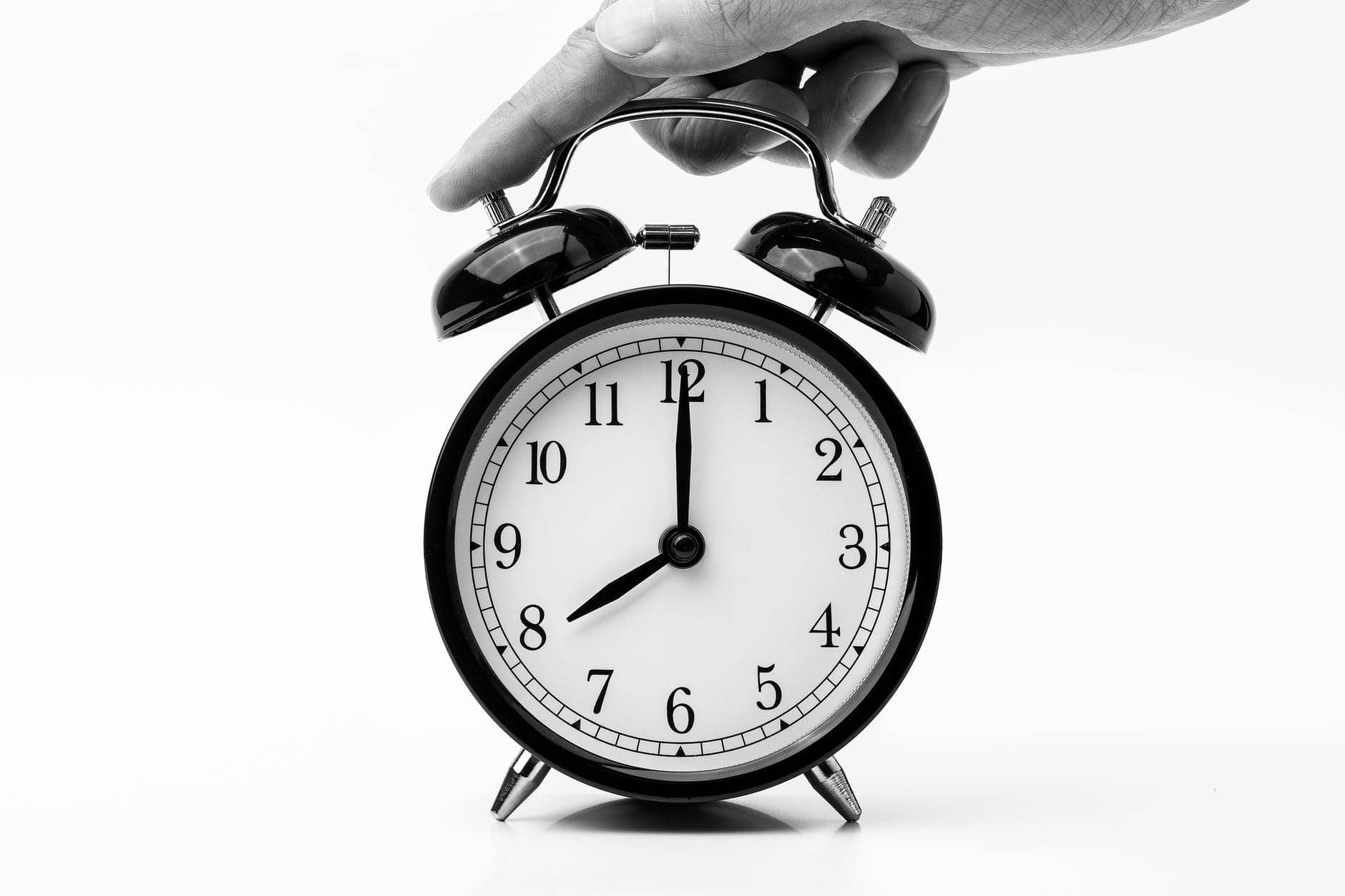 person touching black two bell alarm clock