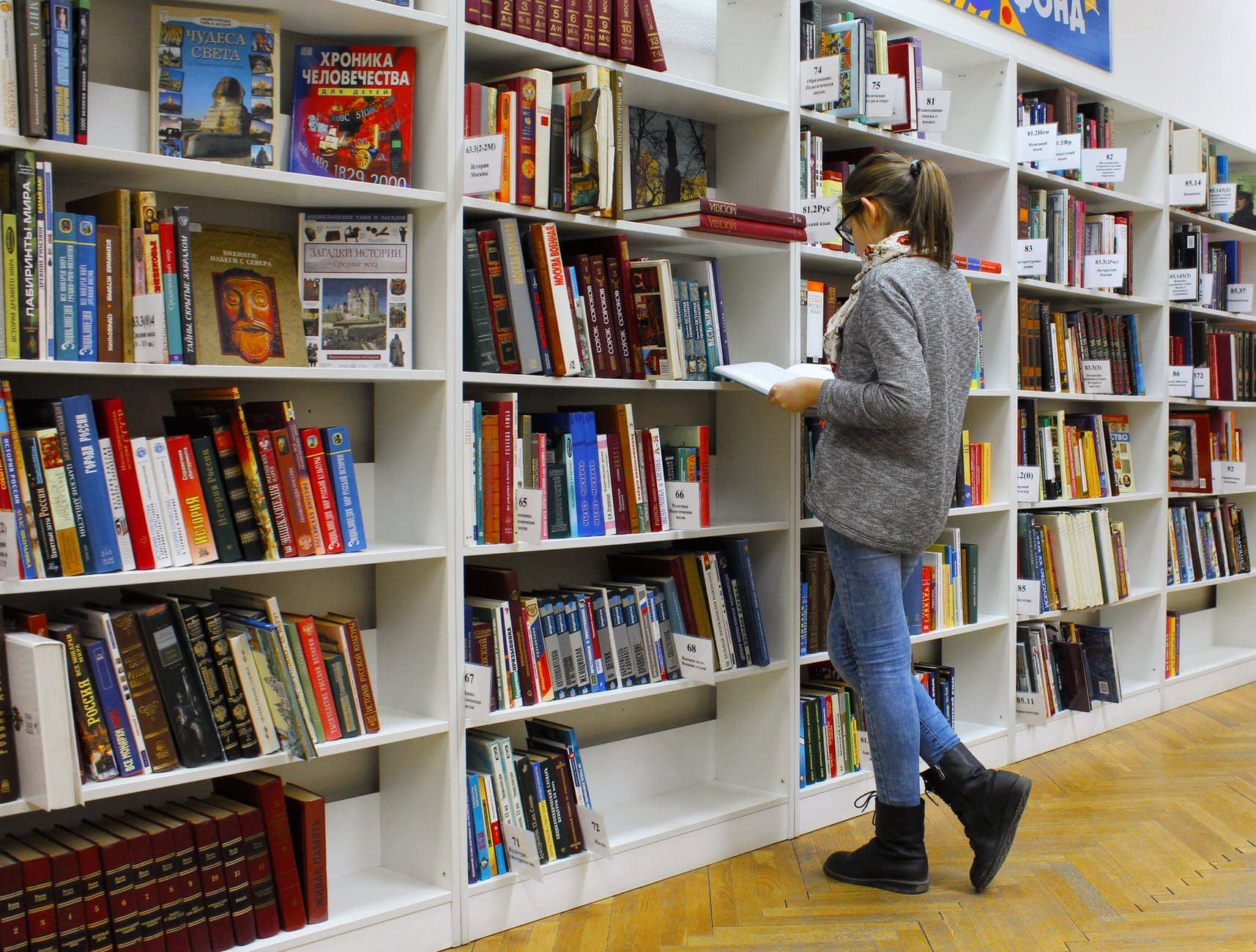 College student using the library to find textbooks so that she can graduate debt free with no tuition loan